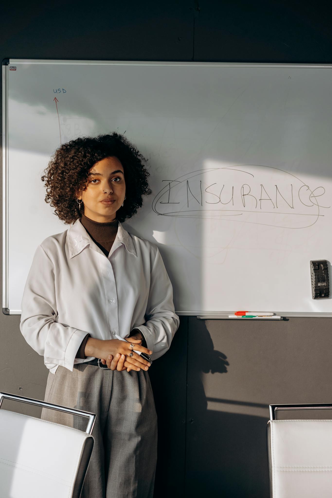 Confident businesswoman presenting on insurance topics in a modern office setting.